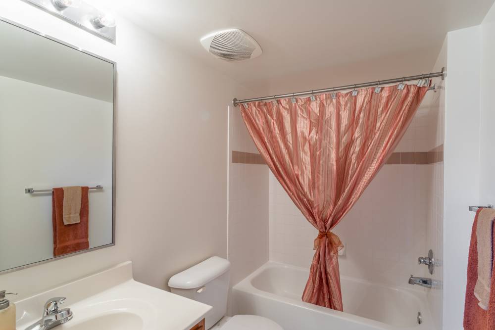 Bright bathroom with sink, commode and bathtub at Corrigan Square Apartments in Gaithersburg, Maryland
