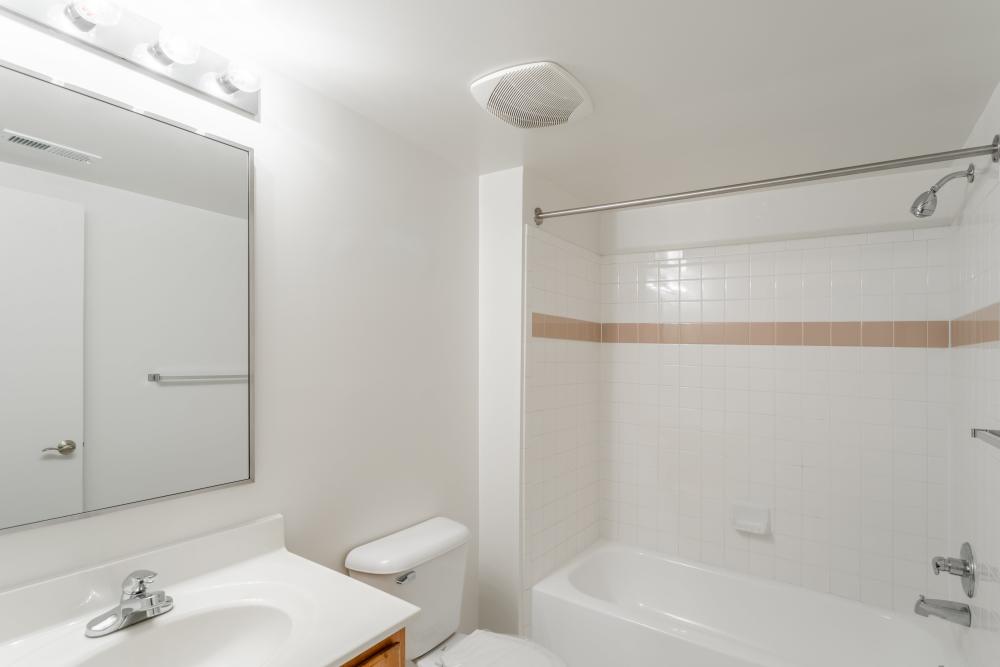 Modern bathroom with vanity light, mirror, sink and bathtub at Corrigan Square Apartments in Gaithersburg, Maryland