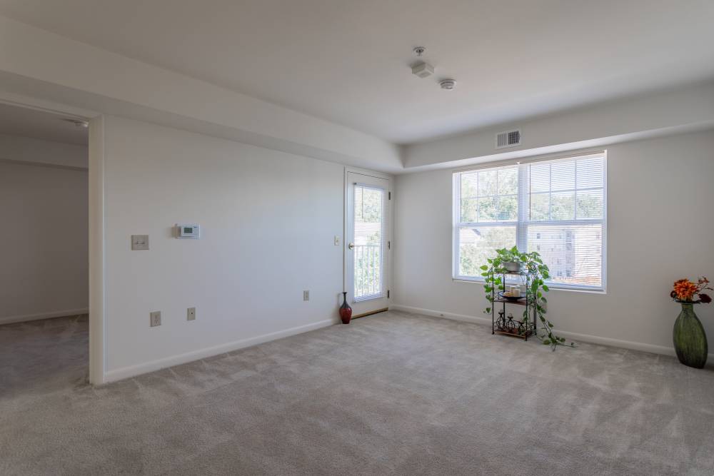 Living room with large window and access to patio at Corrigan Square Apartments in Gaithersburg, Maryland