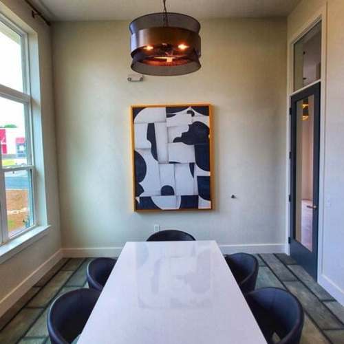 Modern dining area with a white table, black chairs, and contemporary art on the wall at The Mezzanine at Freedom in Charlotte, North Carolina