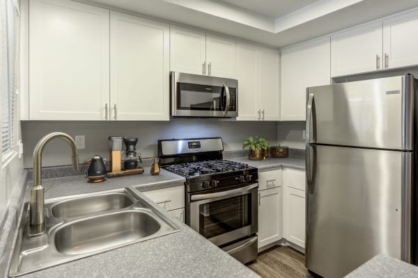 Modern white apartment kitchen with stainless steel appliances at Village Oaks in Chino Hills, CA