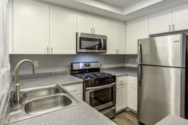 Modern white apartment kitchen with stainless steel appliances at Village Oaks in Chino Hills, CA