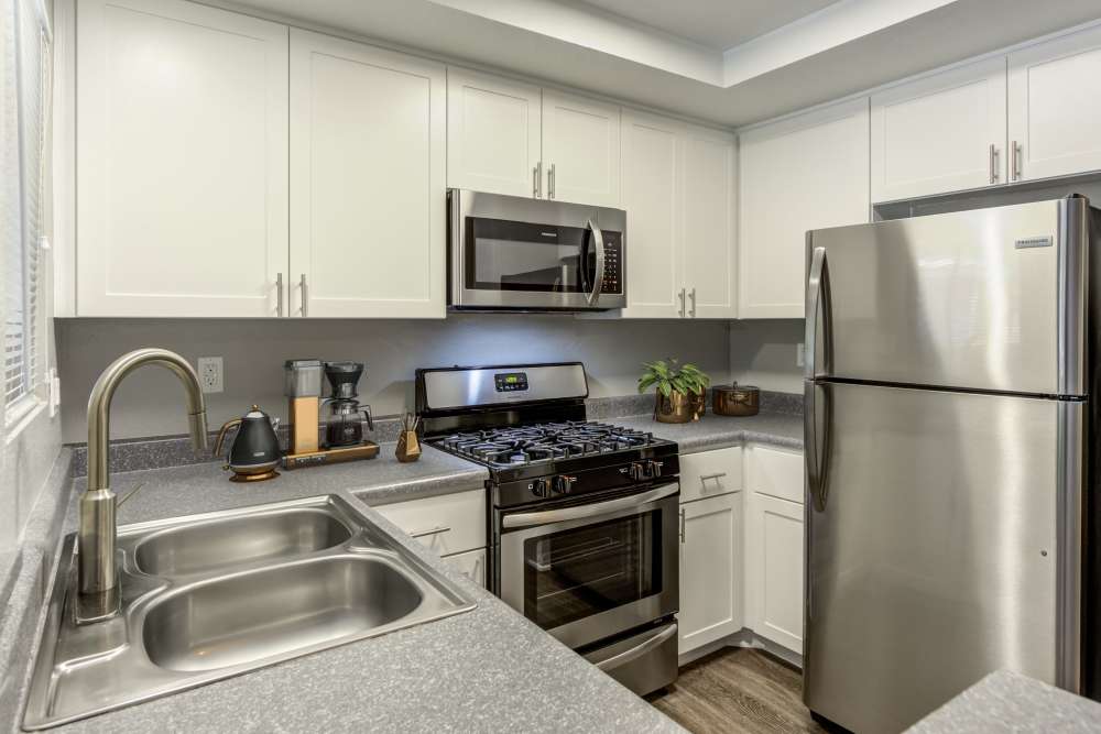 Renovated kitchen with white cabinets and stainless steel appliances at Village Oaks in Chino Hills, California
