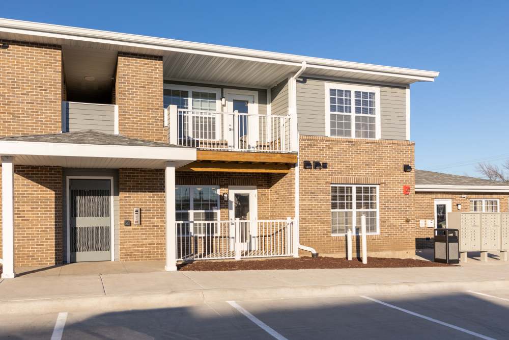 Two-story apartment building with a balcony, gated entrance, and outdoor parking spaces at Anderson Greene I in Cedar Rapids, Iowa