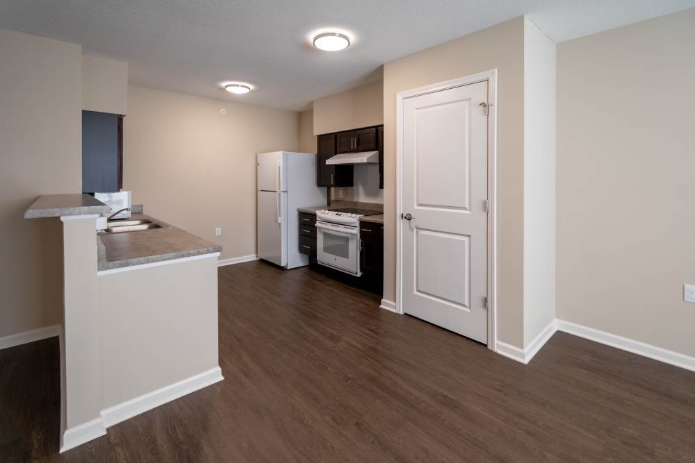 Open layout kitchen with granite countertops, stainless steel appliances, and wood-style flooring at Anderson Greene I in Cedar Rapids, Iowa