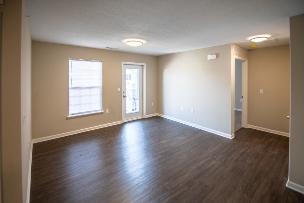 Spacious living area with wood-style flooring and access to a private balcony at Anderson Greene I in Cedar Rapids, Iowa