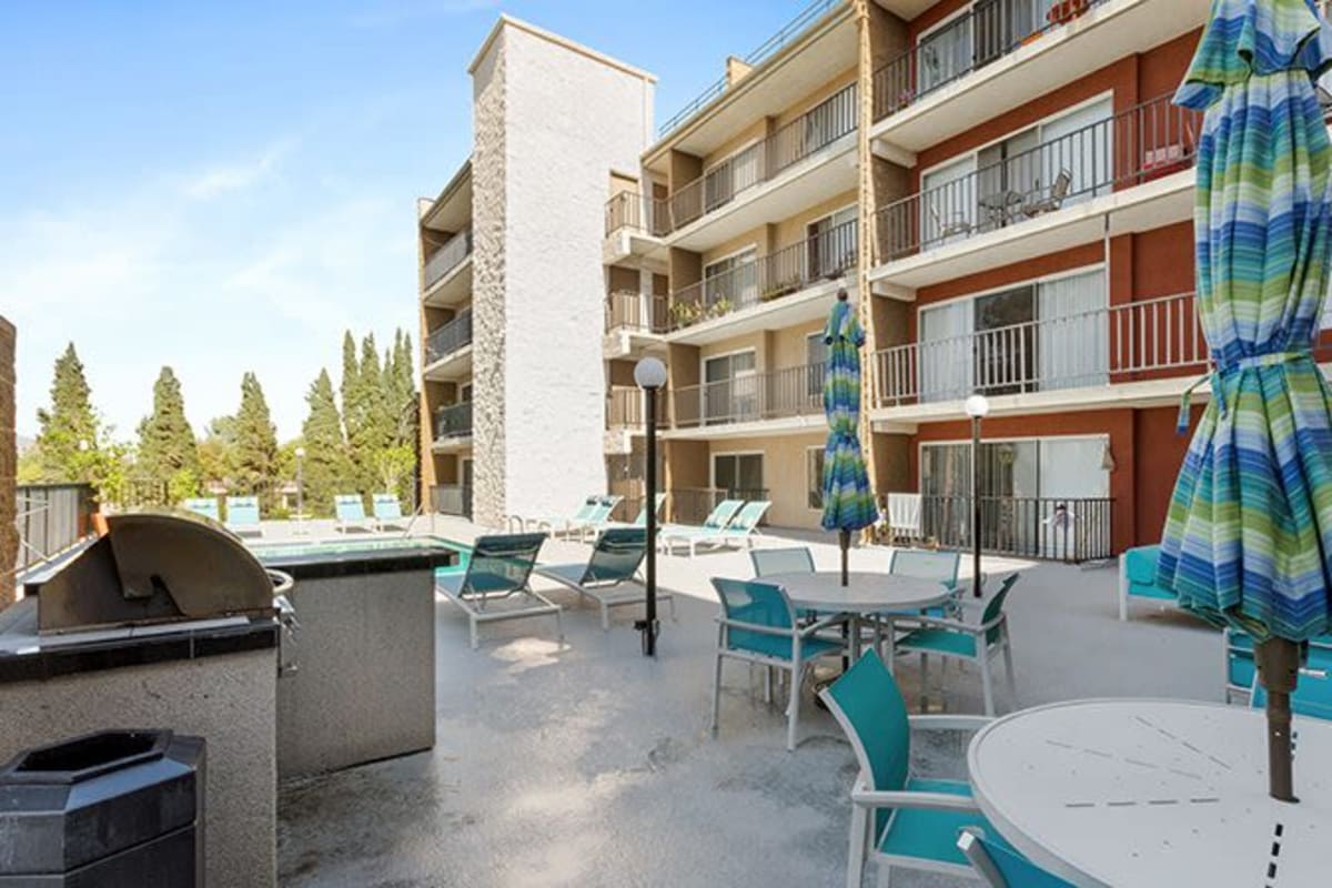 Barbeque area with tables and umbrellas at Amanda Regency Apartments, Van Nuys, California