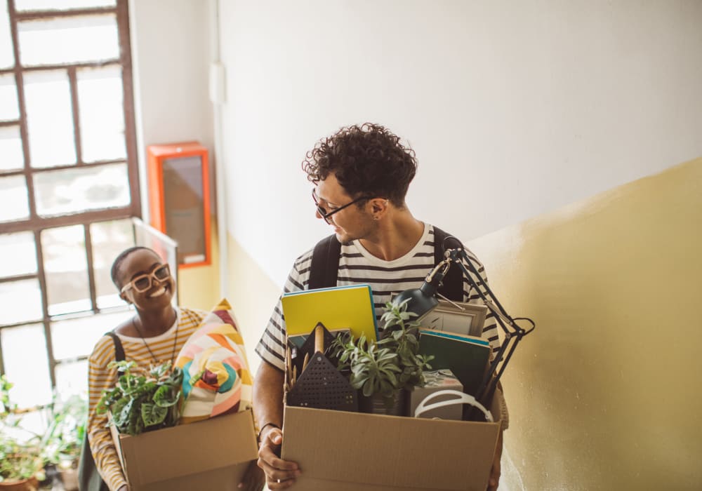 Couple carrying packed boxes upstairs to new home near YourSpace Storage