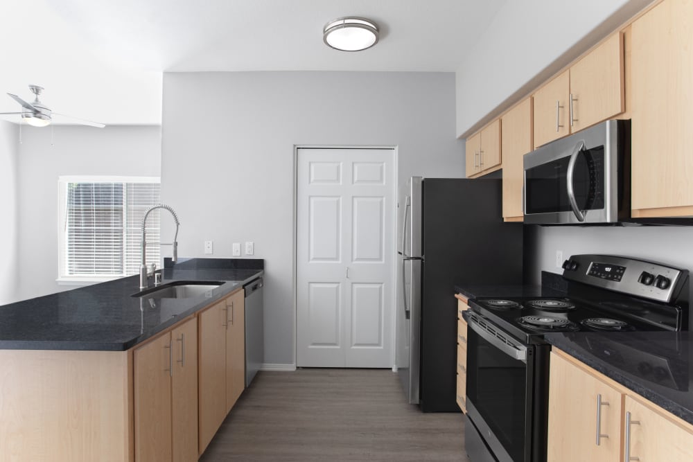 Kitchen with black countertops and ample storage at River Trail Apartments in Puyallup, Washington