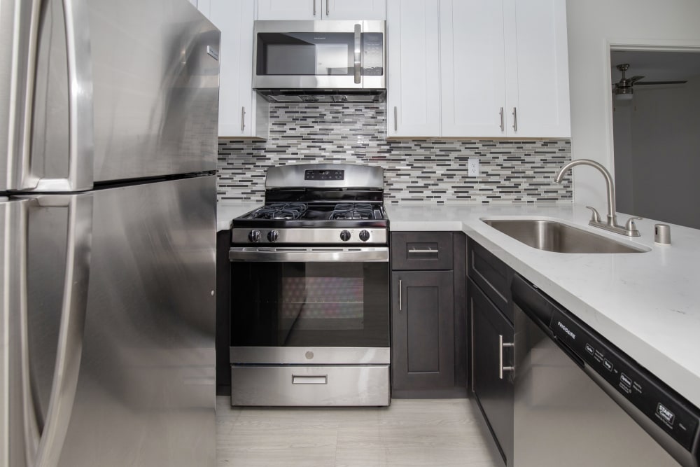 Model kitchen with stainless-steel appliances and a modern backsplash at Club Marina Apartments in Los Angeles, California