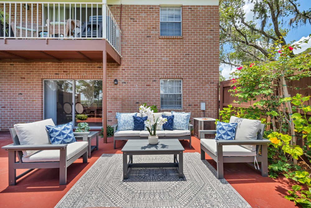 Spacious patio area with couch, chairs, coffee table and plants at Lake Carlton Arms in Lutz, Florida