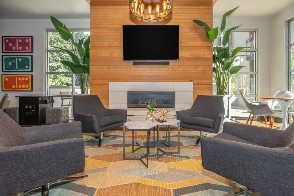 Community clubouse with chairs, tables, fireplace, pendent light and flat screen television at Park Place Olde Town Apartments in Arvada, Colorado