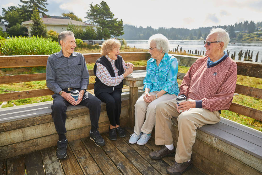 Group of residents chatting and enjoying the sun on patio at Shorewood Senior Living in Florence, Oregon