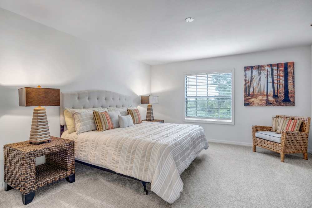 Spacious bedroom with a plush bed, decorative lamps, and a cozy chair by the window at Carlton Arms Of Winter Haven in Winter Haven, Florida