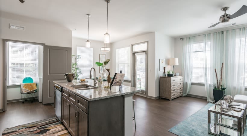 Modern open-concept kitchen and living room with an island and granite counter at The Banks at West Fork in Murfreesboro, Tennessee