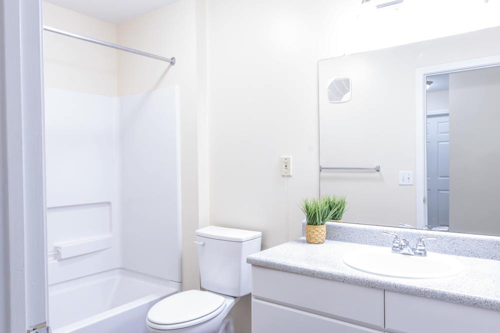 Bright bathroom with mirror, sink, commode and standard bathtub at Ashton Walk in Forest Park, Georgia