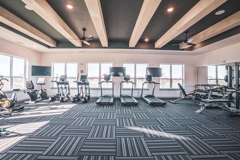 Gym with treadmills, bikes, and weight equipment under exposed ceiling beams at Apex at Perry Crossing in Plainfield, Indiana