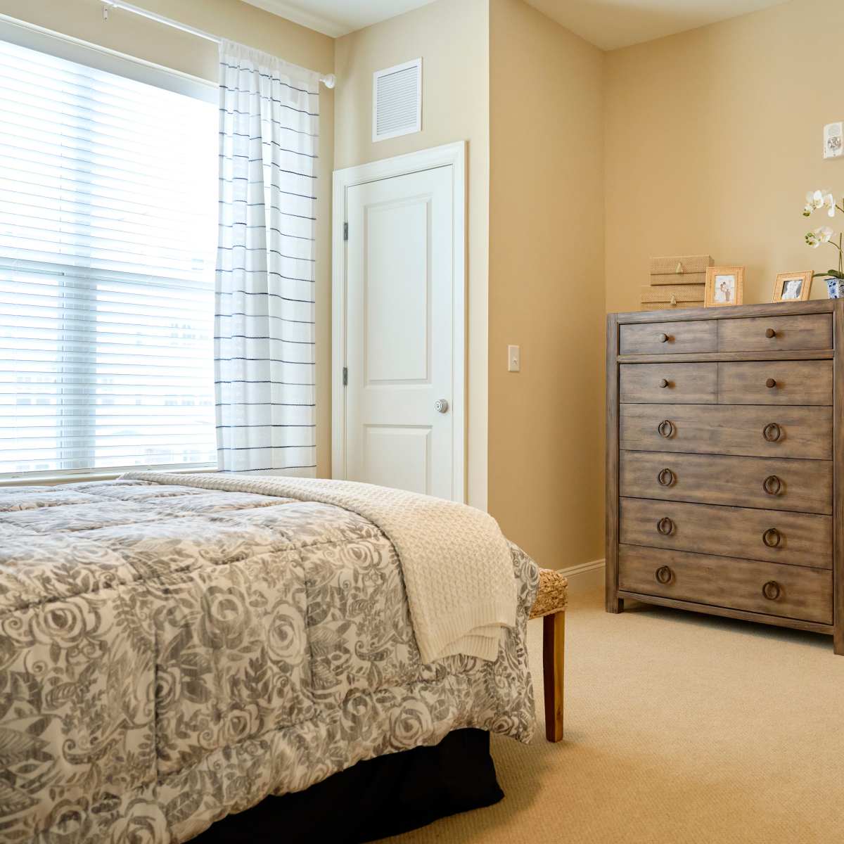 Bedroom with cozy bed and dresser at Harmony at Waldorf in Waldorf, Maryland