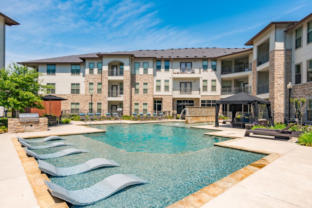 Sparkling pool with loungers in the water at Olympus at Waterside Estates in Richmond, Texas