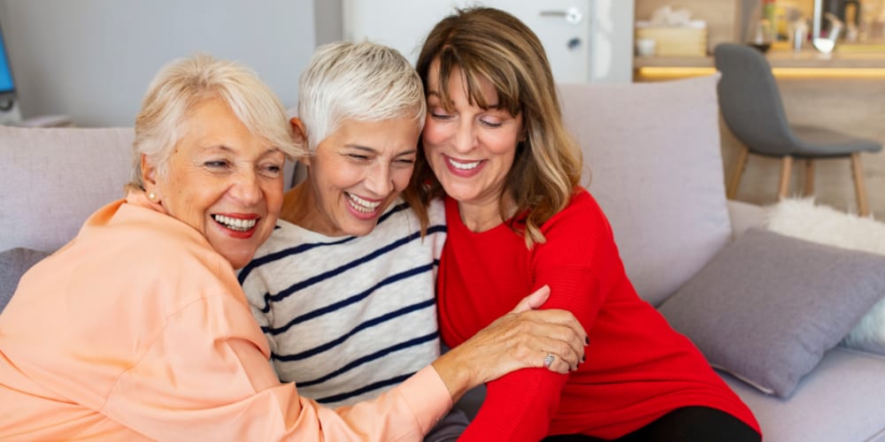 Group of women on a sofa embracing at King City Senior Village in King City, Oregon