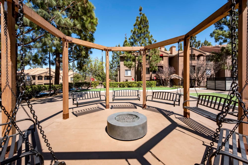 A fire pit surrounded by swings at Sierra Del Oro Apartments in Corona, California