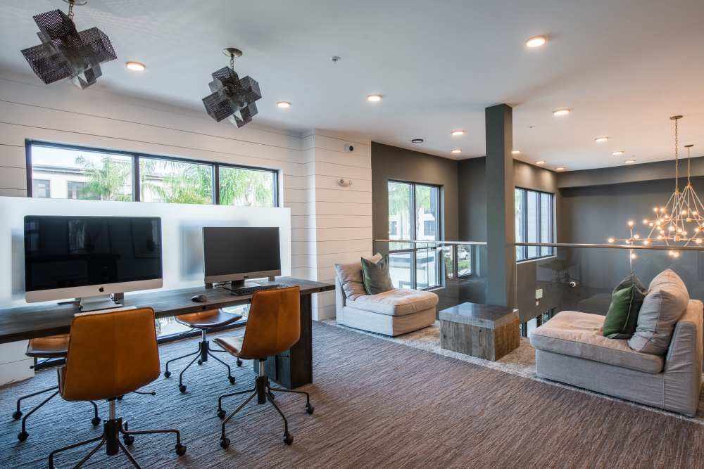 Modern workspace at The Walton in Sanford, Florida featuring stylish seating, sleek computers, and bright natural light.