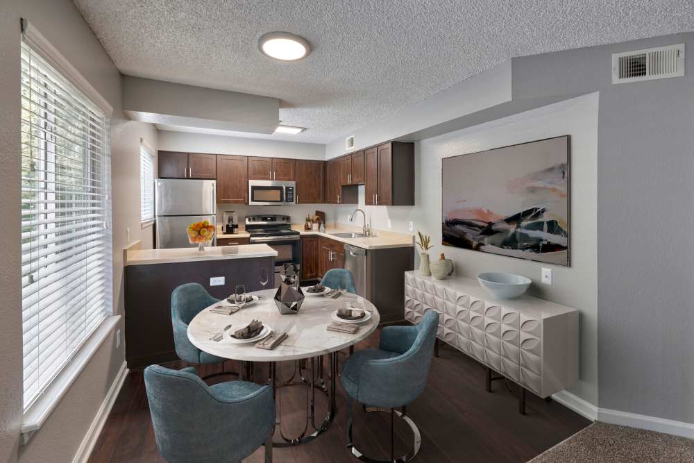 Modern kitchen with stainless-steel appliances and dining area at Arapahoe Club Apartments in Denver, Colorado
