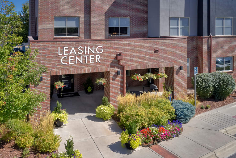 Leasing center entrance surrounded by a lush green landscape at The Rail at Inverness in Englewood, Colorado