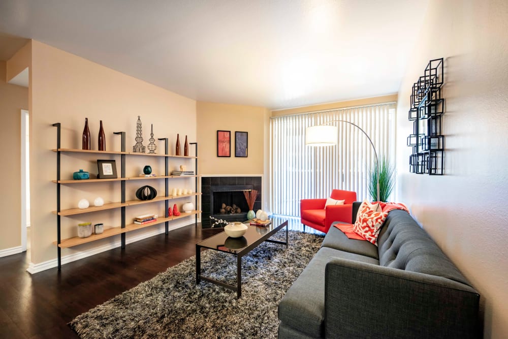 A living room with a fireplace and private patio access at Sierra Del Oro Apartments in Corona, California