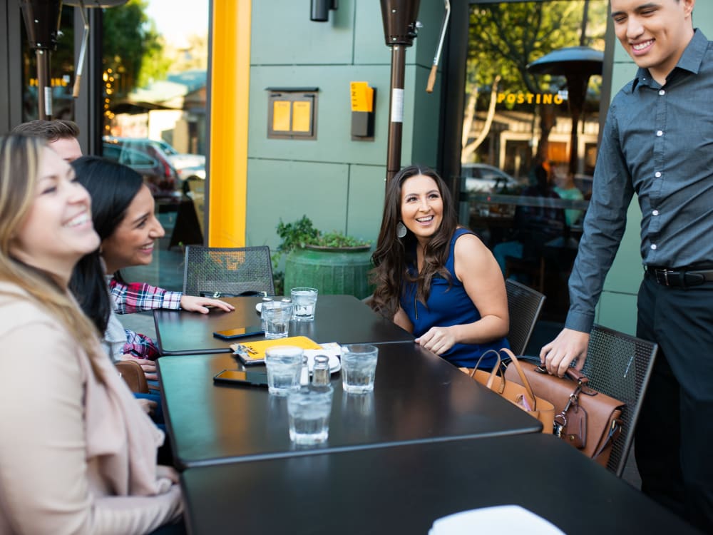 Resident friends enjoying drinks outside at a local bar near San Hacienda in Chandler, Arizona