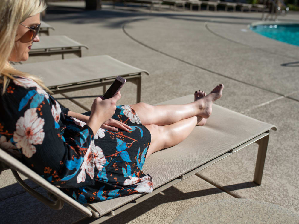 Resident on her iPhone on a lounge chair by the pool at San Milan in Phoenix, Arizona