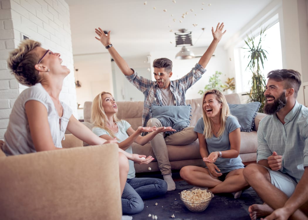 Resident friends eating popcorn and having a ball in their apartment home at The Timbers at Long Reach Apartments in Columbia, Maryland