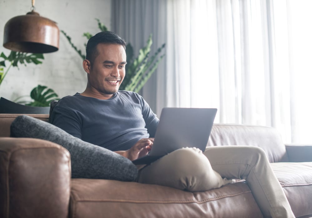 Resident filling out a form on our website on his laptop in his new home at Sofi Warner Center in Woodland Hills, California