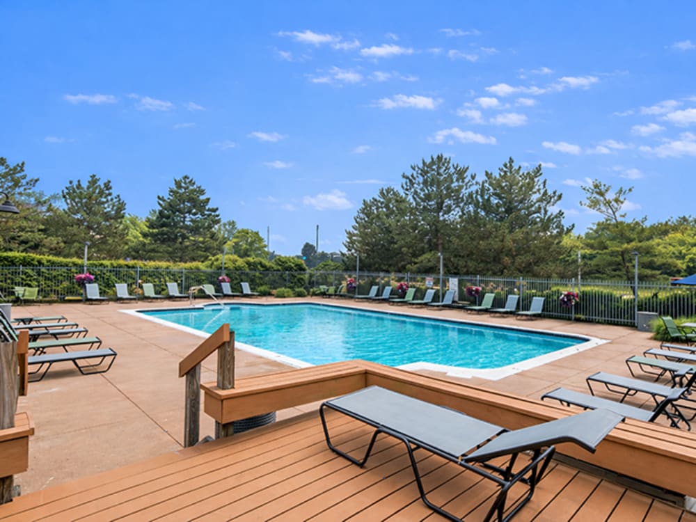 Resort-style pool surrounded by lounge chairs and greenery at Runaway Bay in Lansing, Michigan