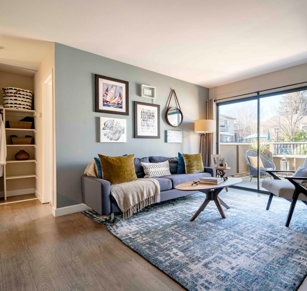 Cozy and well-furnished living space with an accent wall and view of the private balcony outside a model home at Sofi Berryessa in San Jose, California