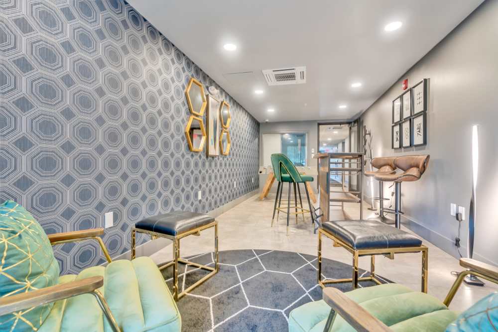 Green chairs with gold accents and patterned wall at Latitude at South Portland in Portland, Maine
