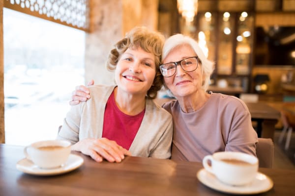 Two elderly woman embracing in the dining hall at English Meadows Teays Valley Campus in Scott Depot, West Virginia