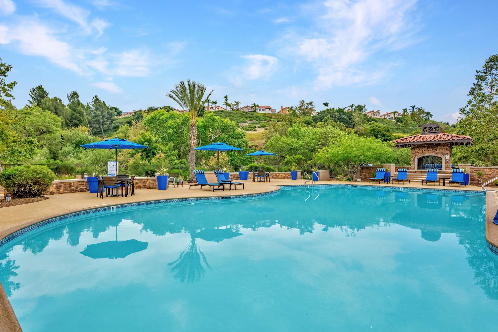 Swimming pool with sun-shades and lounge beds at Palisades Sierra Del Oro in Corona, California