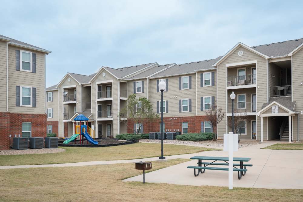 Charming community featuring spacious buildings, inviting picnic areas, and a fun playground amidst lush landscaping at Cascade Villas in Wichita Falls, Texas