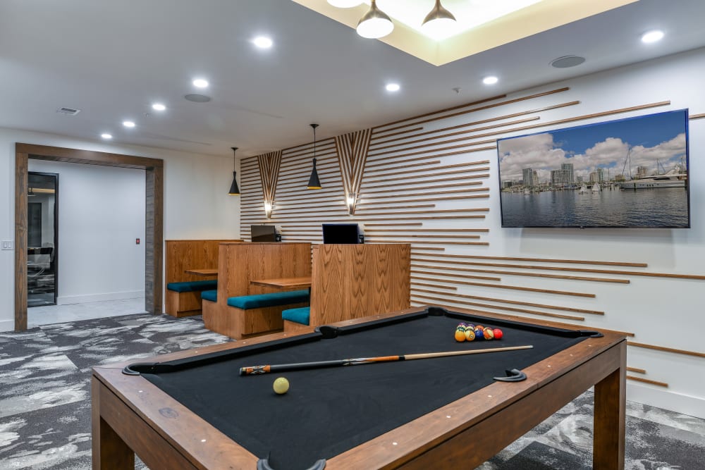 Resident game room with bar, hanging lights, and pool table at SoBA Apartments in Jacksonville, Florida