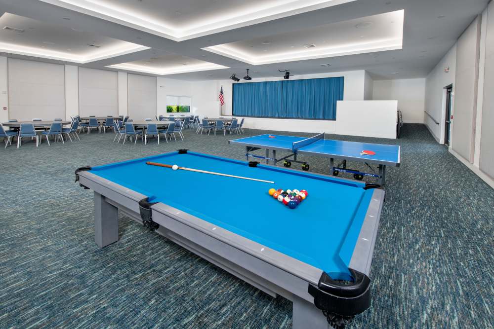 Bright community room with blue pool table and ping pong tables, seating areas in the background at Solera at Avalon Trails in Delray Beach, Florida
