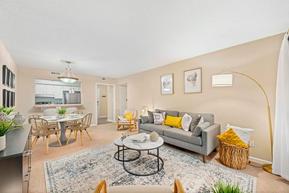 Spacious living room with couch, coffee table, chairs, and hard-wood style flooring at The Ellery of Cary in Cary, North Carolina