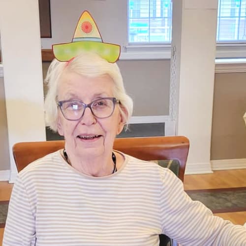 A resident sitting at a table with a fun hat on at Homestead House in Beatrice, Nebraska