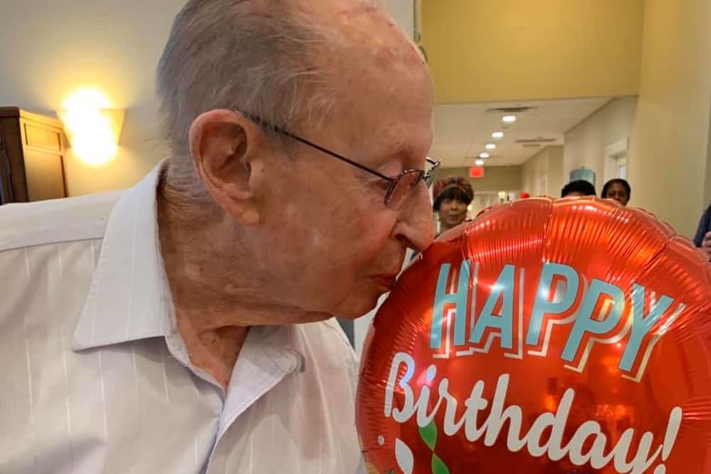 A resident kissing a Happy Birthday balloon at Inspired Living Bonita Springs in Bonita Springs, Florida.