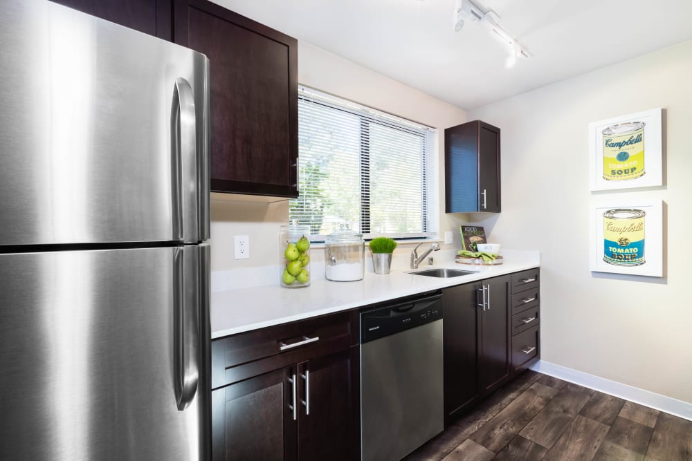 Large kitchen with a stainless steel refrigerator and dishwasher in a model home at Madison Sammamish Apartments in Sammamish, Washington