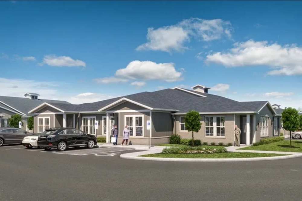Exterior view of the apartment building with cars parked at Magnolia Living in League City, Texas