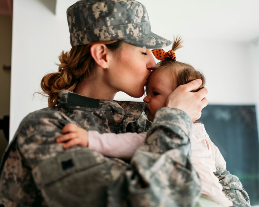 A mother in a military uniform kissing her daughter at Capeharts in Ridgecrest, California