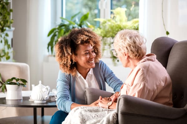 Younger woman kneeling down talking to an elderly woman at Harbor Village Senior Communities in South Burlington, Vermont