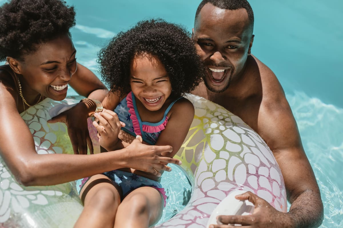 Happy family swimming in the pool at The District Flats in West Palm Beach, Florida