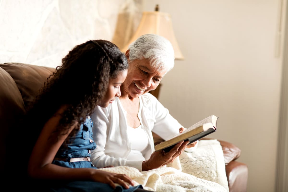 A resident and child reading a book together at Carnegie Heights at Henderson in Henderson, Nevada